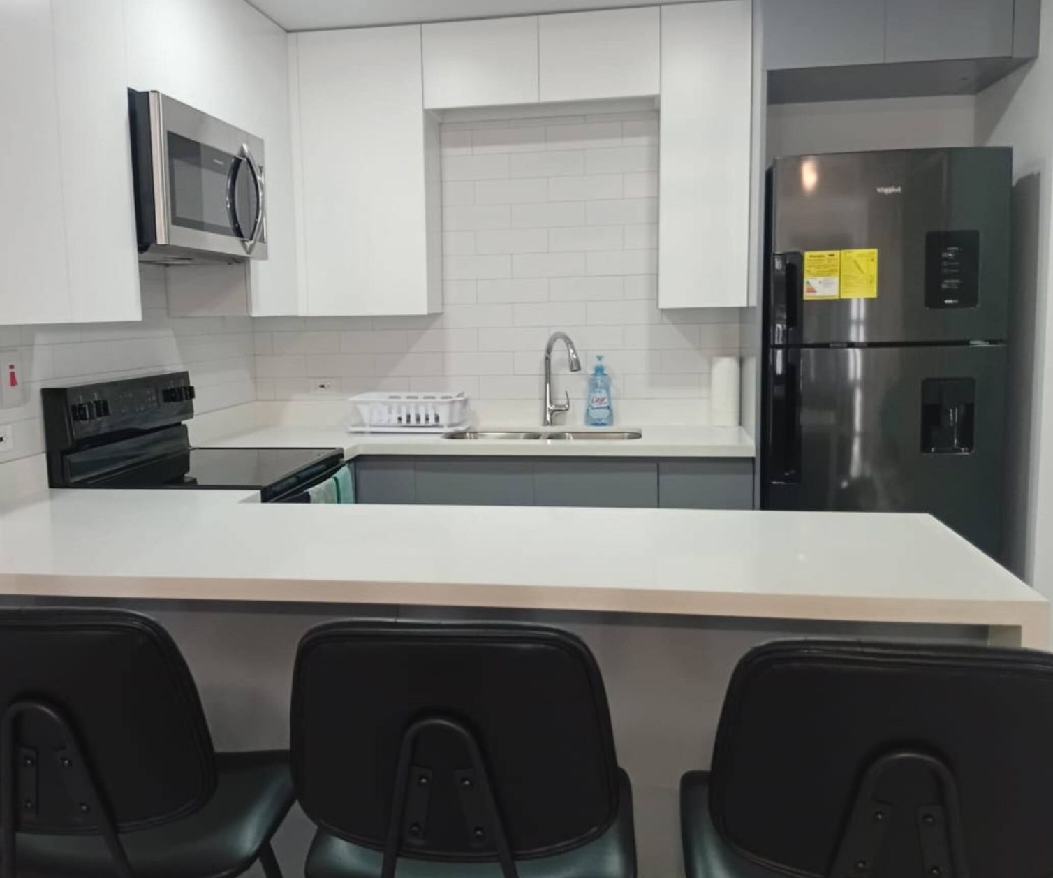 A modern kitchen with white cabinets, stainless steel appliances, and a central island with bar stools.