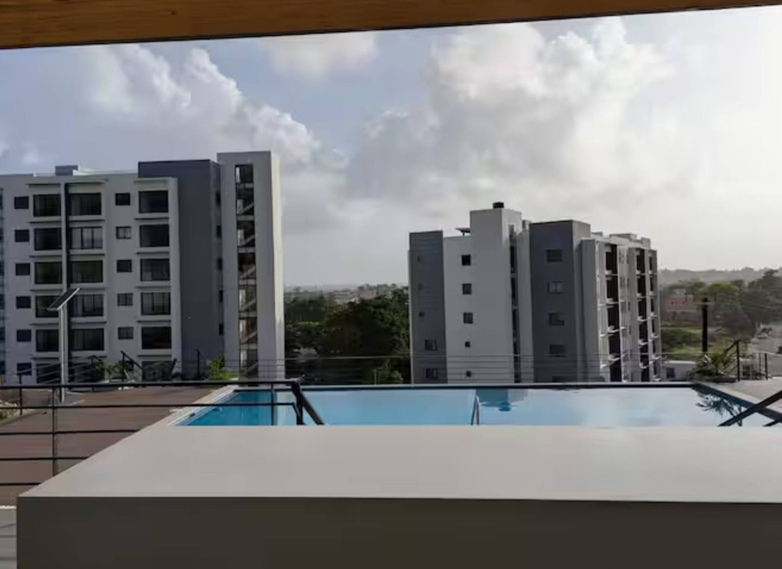 A modern building with a pool in the foreground and other residential buildings in the background.