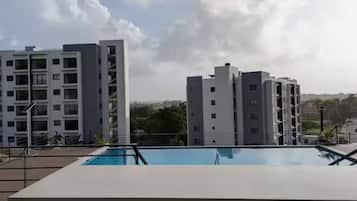 A modern building with a pool in the foreground and other residential buildings in the background.