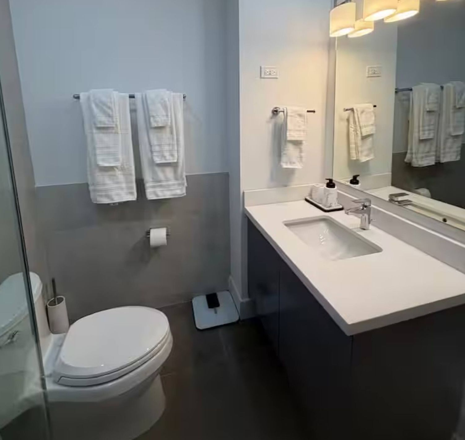 A modern bathroom with a white sink, mirror, and two towels hanging on the wall.