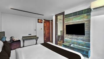 A hotel room with a bed, bedside table, lamp, and a television mounted on a wall with a decorative panel.