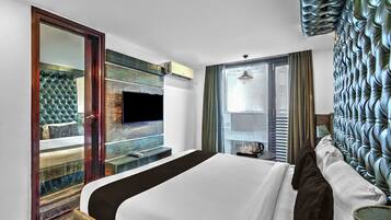 A hotel room with a bed, a television mounted on the wall, a window with curtains, and a decorative wall panel.