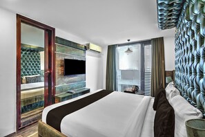 A hotel room with a bed, a television mounted on the wall, a window with curtains, and a decorative wall panel. - Townhouse Oak Hotel Banjara Hill (Hyderabad)
