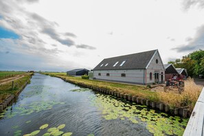 A riverside property with a large house, a smaller building, and a red vehicle. - Farmhouse Retreat for 20 Guests in Snelrewaard (Snelrewaard)
