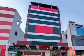 Edifício de vários andares com design arquitetônico moderno, destacando uma fachada listrada e entrada no térreo com sinalização.