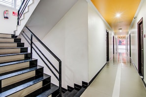 A hotel corridor with a staircase, a fire extinguisher, and a hallway leading to rooms. - Collection O Saraswathi Park (Visakhapatnam)