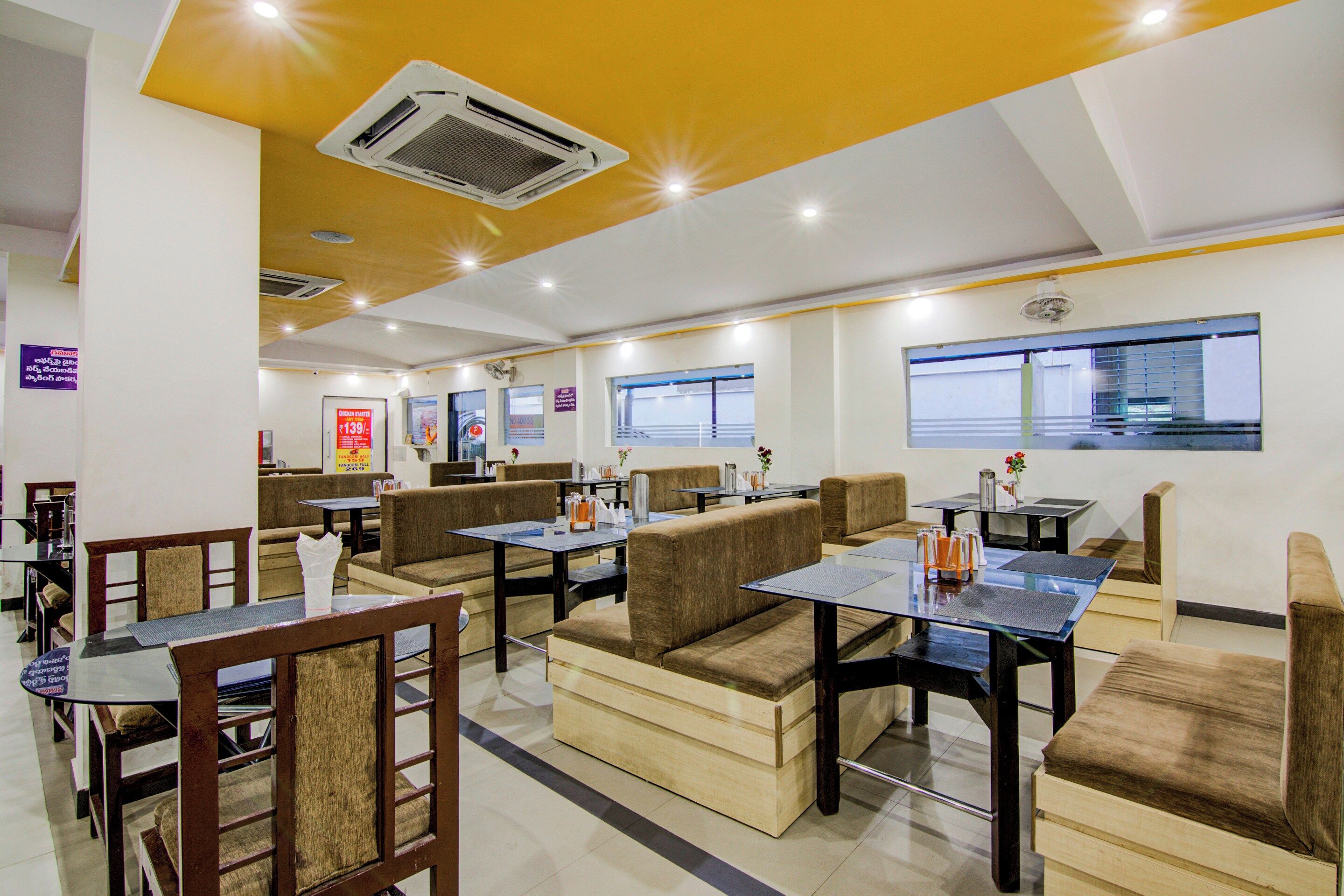A restaurant with booths and tables, ceiling fans, and a view of the outside.