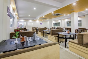 Um restaurante com cabines e mesas, algumas com assentos fixos.