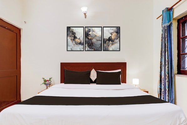 A hotel room with a large bed, a wooden headboard, a nightstand with a lamp, and a window with curtains. - Hotel O Clement Town (Dehradun)