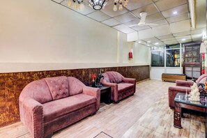 A reception area with two sofas, a small table, and a decorative statue. - Hotel O Clement Town (Dehradun)