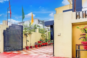A gated courtyard with potted plants and a building in the background. - Hotel O Clement Town (Dehradun)