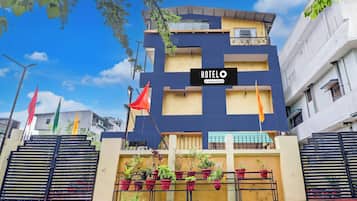 A multi-story building with a sign reading 'HOTEL' and a balcony with potted plants.