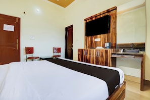 Una habitación de hotel con cama, escritorio con cafetera, televisor y armario.