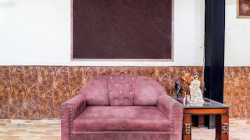 Una habitación con un ventanal grande, un sofá, una mesita baja con adornos y un papel tapiz estampado.