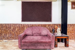 Una habitación con un ventanal grande, un sofá, una mesita baja con adornos y un papel tapiz estampado.