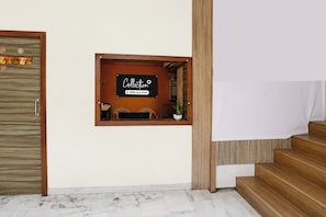 Un área de recepción con un cartel que dice 'Collection' y una pequeña zona de estar con una planta.