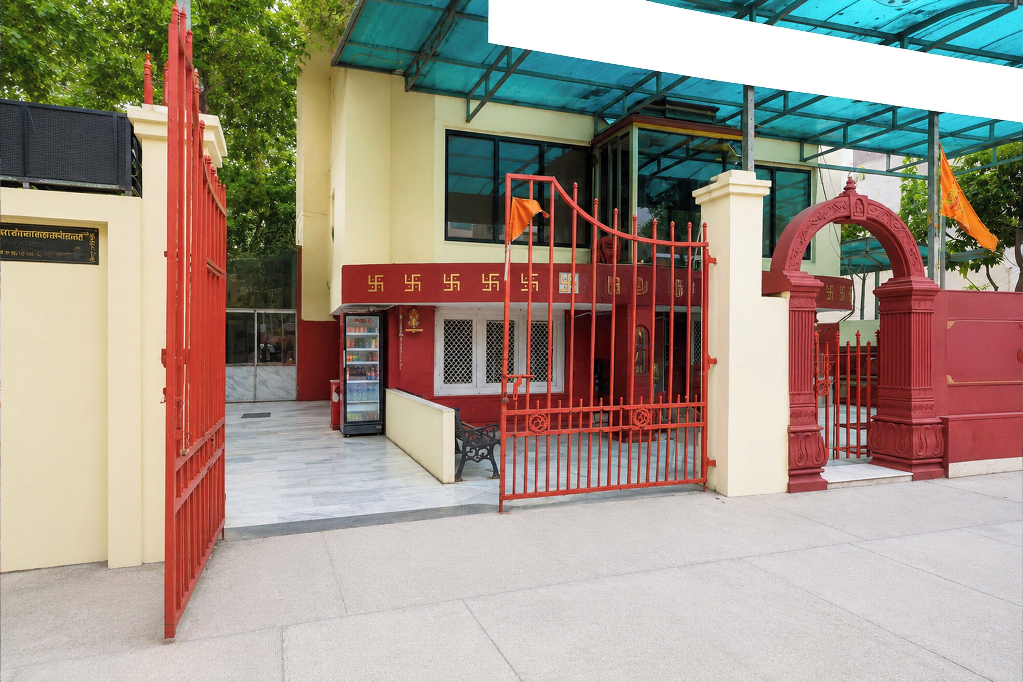 A building entrance with a red gate, a covered area with a blue roof, and a sign with text.