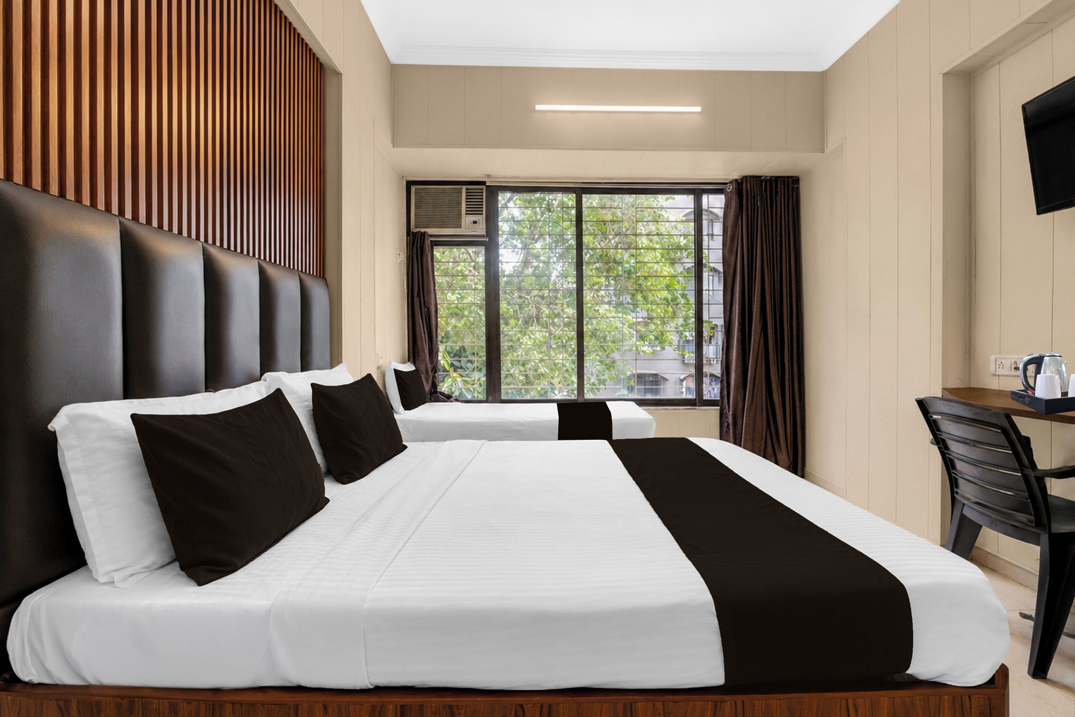 Habitación de hotel con dos camas, un escritorio y una ventana con cortinas.
