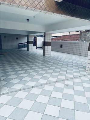 Ein geräumiger Innenbereich mit Schachbrettmuster-Boden, gefliesten Wänden und einer sichtbaren Treppe zu einer oberen Ebene.