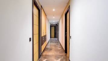 A corridor with doors on both sides, a tiled floor, and a ceiling with recessed lighting.