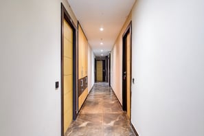 Un pasillo con puertas a ambos lados, piso de baldosas e iluminación empotrada en el techo.