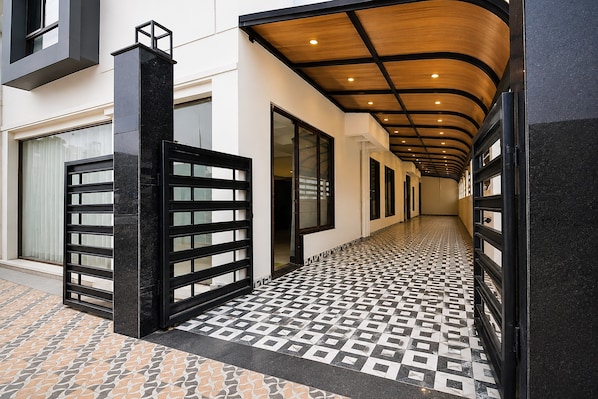 A corridor with a patterned floor, a black gate, and a wooden ceiling. - Townhouse Newtown DLF (Barasat)