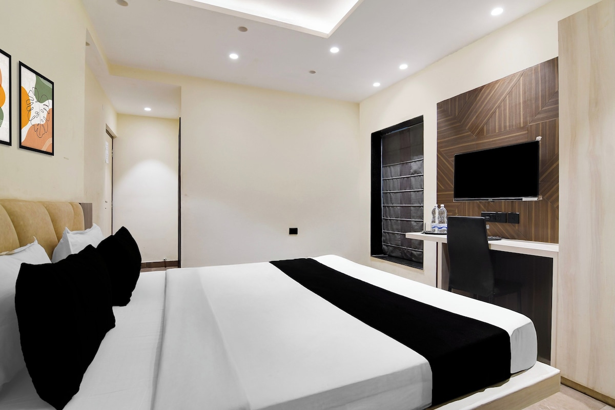 A modern hotel room with a bed, a desk, a TV, and a window.