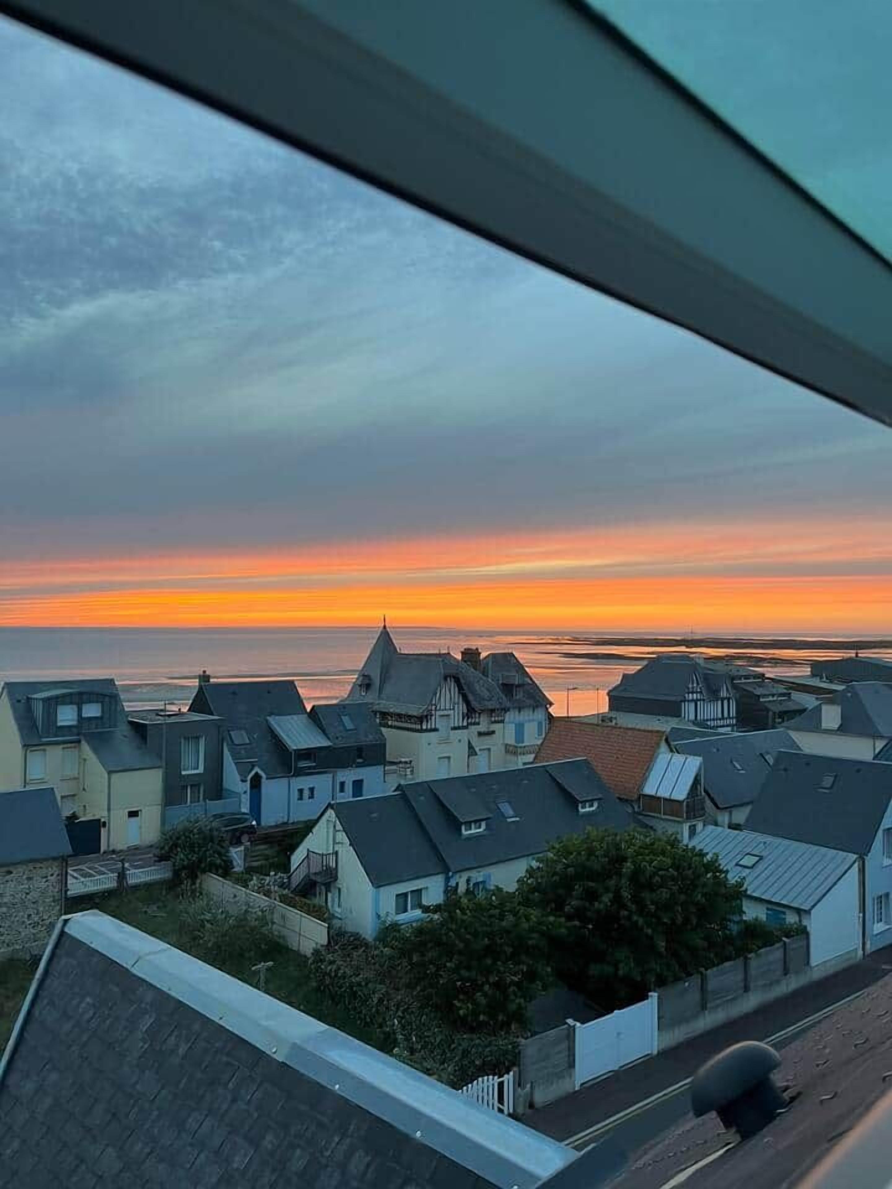 Un barrio residencial con casas y vista al mar al atardecer.
