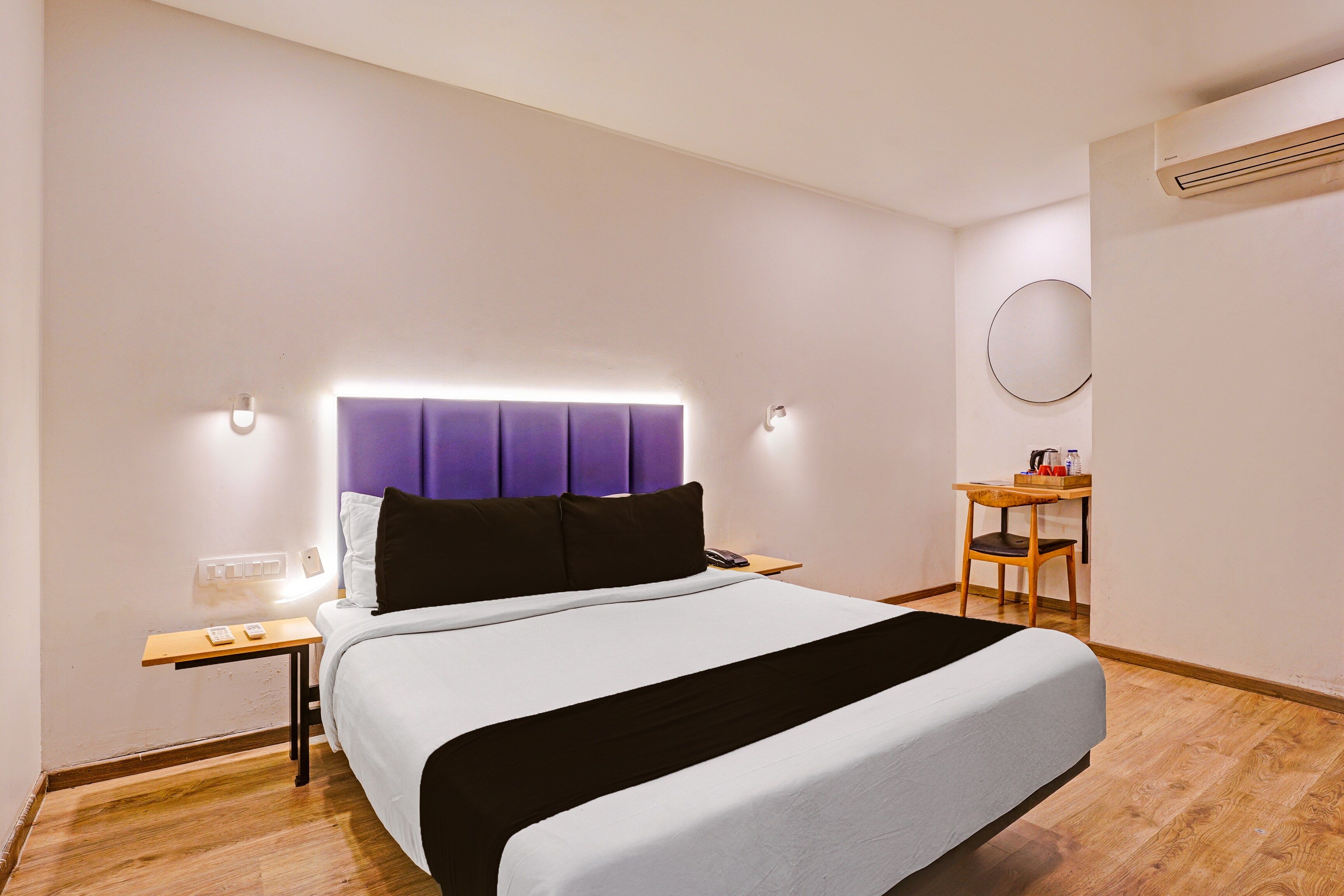 Una habitación de hotel con cama, mesita de noche y un pequeño escritorio con silla.