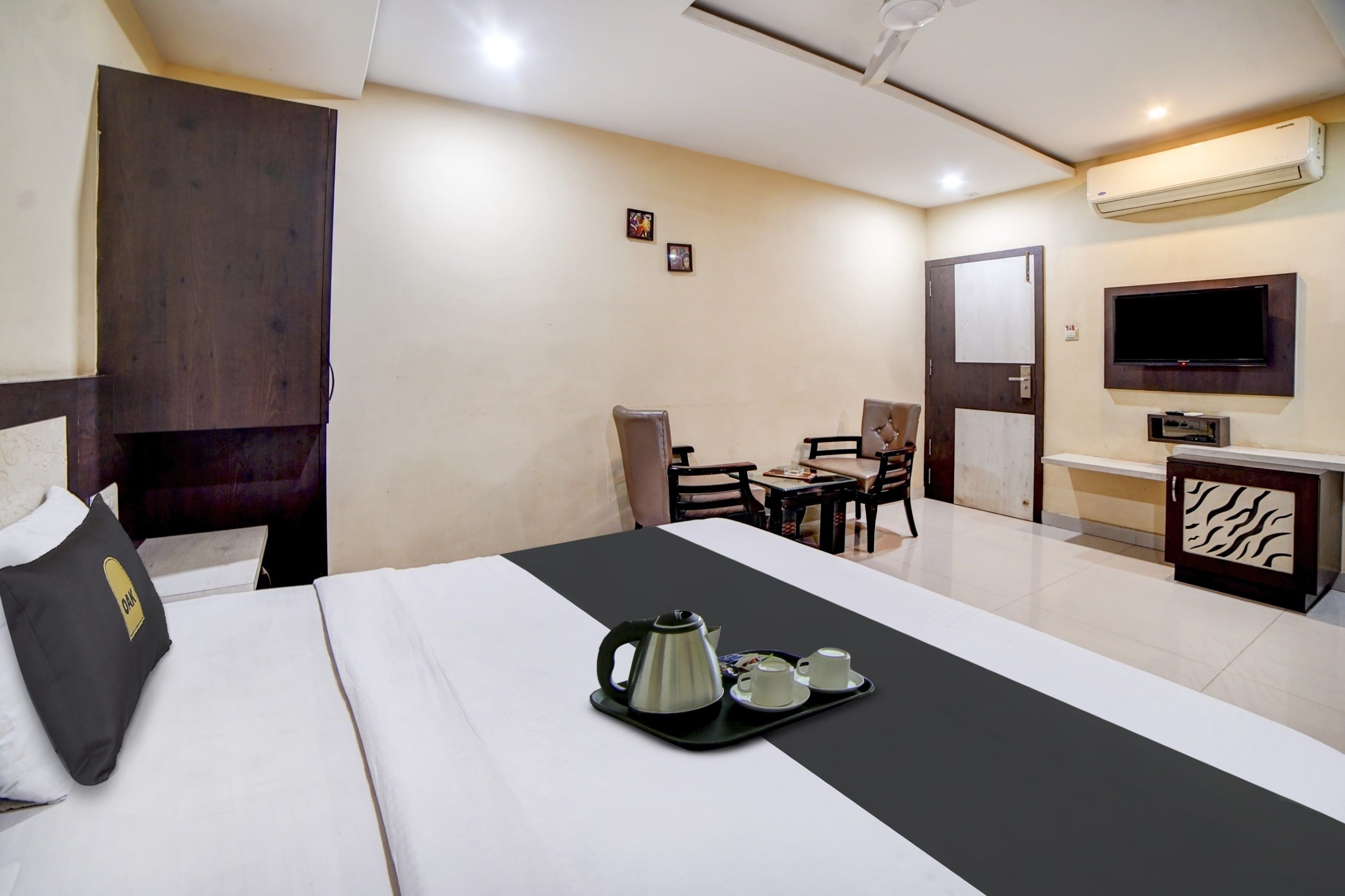 Une chambre d’hôtel équipée d’un lit, d’un bureau, d’une chaise, d’une télévision et d’un plateau de courtoisie avec du café.