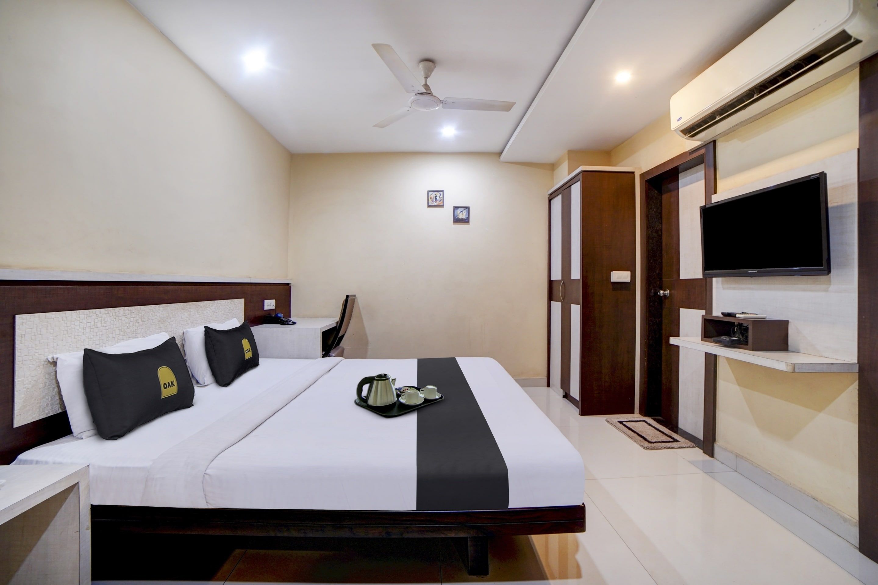Une chambre d’hôtel équipée d’un lit, d’un ventilateur de plafond, d’un climatiseur, d’une télévision et d’une armoire.
