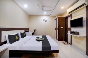 Una camera d'albergo con un letto, una ventola a soffitto, un condizionatore, una televisione e un armadio.
