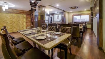 Un espace repas avec une longue table dressée pour accueillir plusieurs personnes, entourée de chaises rembourrées.