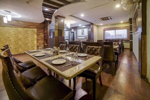 Zona pranzo con un tavolo lungo apparecchiato per diverse persone, circondato da sedie imbottite.