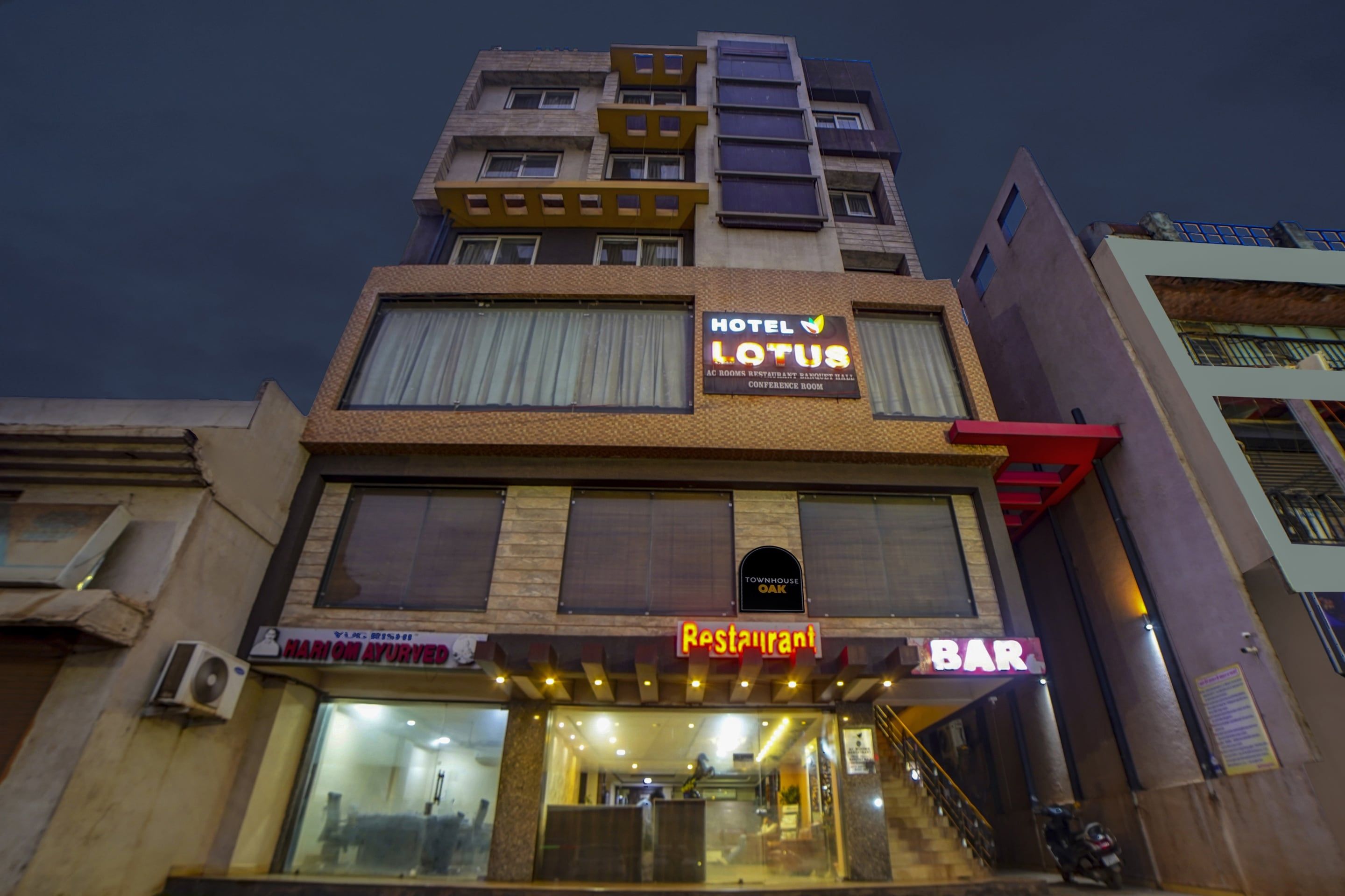 Un immeuble à plusieurs étages, sur lequel on peut lire l’enseigne « Hôtel Lotus », indiquant qu’il propose des chambres climatisées, un restaurant, une salle de banquet et une salle de conférence.