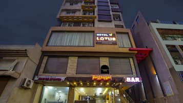 Un immeuble à plusieurs étages, sur lequel on peut lire l’enseigne « Hôtel Lotus », indiquant qu’il propose des chambres climatisées, un restaurant, une salle de banquet et une salle de conférence.