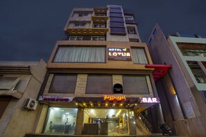 Um edifício de vários andares com uma placa indicando 'Hotel Lotus', oferecendo quartos com ar condicionado, restaurante, salão de festas e sala de conferências.