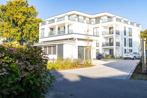 A modern multi-story residential building with balconies, a driveway, and a well-maintained garden. - Holiday apartment with 1 bedroom (Ostseebad Zingst)