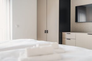 A hotel room with a bed, a wardrobe, and a television mounted on the wall. - Holiday apartment with 1 bedroom (Ostseebad Zingst)