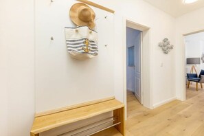 A hallway with a wooden bench, a hat, and a striped bag hanging on the wall. - Holiday apartment with 1 bedroom (Ostseebad Zingst a Darß)