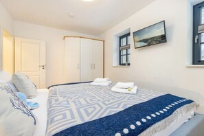 A hotel room with a bed, a wardrobe, a window with a view, and a painting on the wall. - Holiday apartment with 1 bedroom (Ostseebad Zingst a Darß)