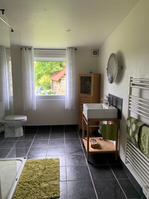 Un baño con inodoro, lavamanos, espejo y ventana con cortinas.
