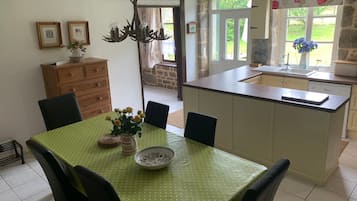 Un comedor con mantel verde, sillas, un armario de madera y una lámpara de araña.