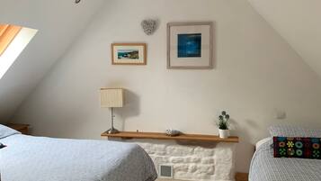 A bedroom with two beds, a wooden headboard, a white wall, and a ceiling light fixture.