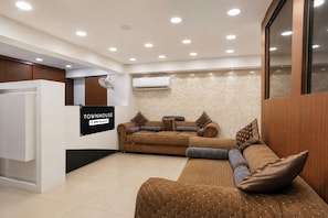 A modern living room with a sofa, a coffee table, and a sign indicating 'TOWNHOUSE OYO-Serviced'. - Townhouse Oak Central Bus Station Rajkot (Rajkot)