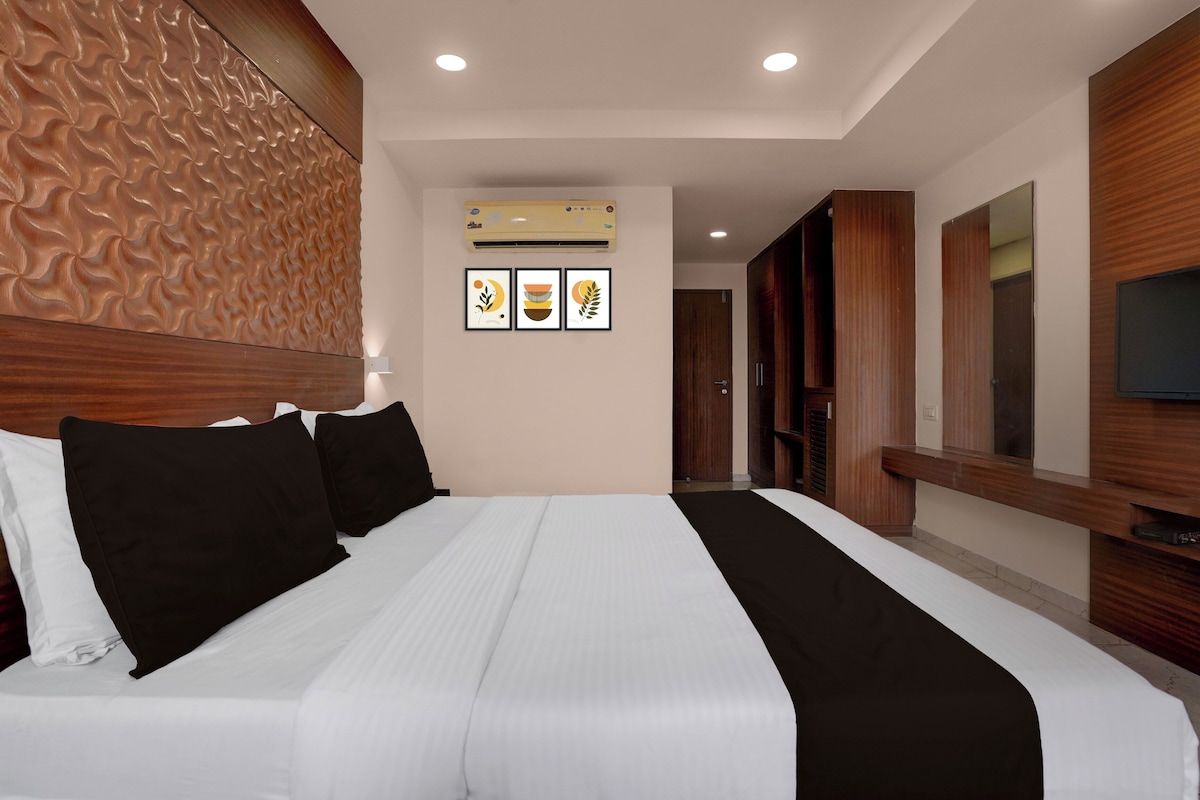 Habitación de hotel con una cama grande, cabecero de madera, televisor de pantalla plana y aire acondicionado de pared.
