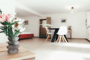 Ein modernes Wohnzimmer mit Essbereich, einem roten Sofa und einem weißen Stuhl.