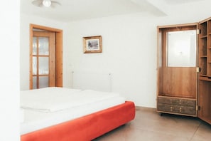 Ein Schlafzimmer mit einem Bett, einem Holzschrank, einer Tür und einem gerahmten Bild an der Wand.