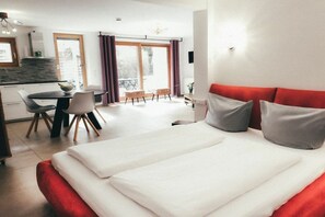 A modern hotel room with a large bed, a dining area, and a kitchen. - House Luna - Apartment Luna 5 (Schwangau)
