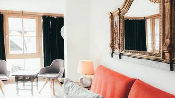 A room with a sofa, two armchairs, a table, a lamp, and a mirror.